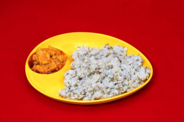 Gujarati Kathiyawadi 'nin yakın plan görüntüsü Baharatlı Dhokali Sabji Khichdi ile, sarı tabakta, kırmızı arka planda