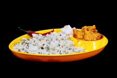 Side view of Gujarati Kathiyawadi Spicy Dhokali Sabji with khichdi and red chili, on yellow dish prominently, set against a black background clipart