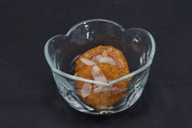 The traditional delicacy Mohanthal, served in a small glass bowl containing two pieces clipart