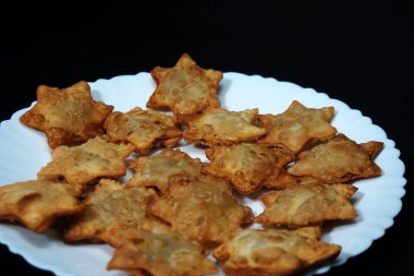 Siyah arka planda sergilenen domates sosuyla birlikte Aloo Puff Pastasının yer aldığı bir tabak..