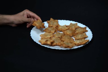 Tabakta domates sosu olan Aloo Puff Pastası, siyah arka planla çelişiyor..