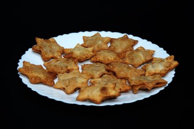 Bir tabak Aloo Puff Pastası ve domates sosu, siyah arka planda sunuluyor..