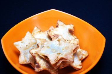 Üzerinde yıldız şekilli Aloo Puff Pastası olan bir kase. Yanında da domates sosu..