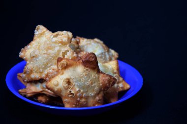 Mavi bir tabakta küçük bir kase domates sosuyla süslenmiş Aloo Puff Pastası..