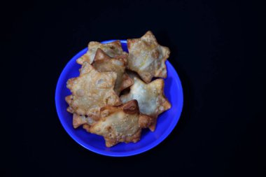 Yanında domates sosuyla süslenmiş Aloo Puff Pastası olan mavi bir tabak..