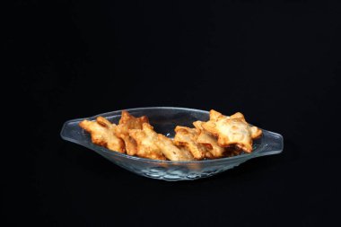 Kızarmış tavuk kanatlarıyla dolu cam bir kase altın-kahverengi bir renk ve iştah açıcı bir dokuya sahip..