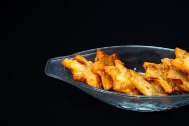 Kızarmış tavuk kanatlarıyla dolup taşan cam bir kase, kıtır kıtır ve zengin bir dış görünüşü var..