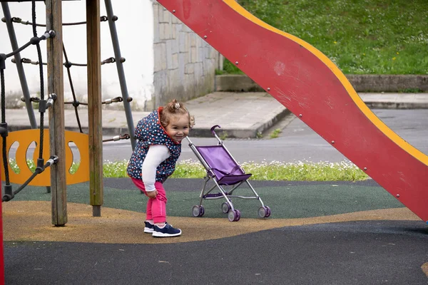 1 yaşında bir kız bebek arabasıyla salıncakta sallanıyor. aile kavramı