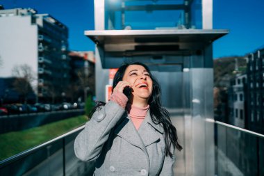 Yakın plan yönetici esmer kadın iş merkezinde cep telefonuyla yüksek sesle gülerek konuşuyor. İş kadını kavramı