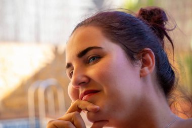 Güzel gülümseyen ve eli çenesinde dinlenen düşünceli bir kadının yakın çekimi. güzellik konsepti