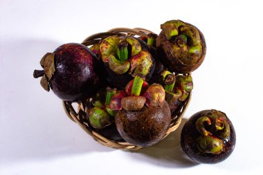 İçinde taze mangosteen meyvesi olan küçük bir bambu sepeti.