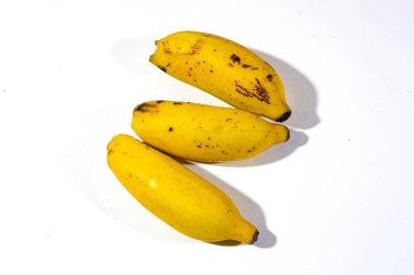 Üç küçük muz, parlak sarı, düz beyaz arka planda düzgün bir şekilde sunuluyor.