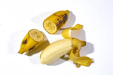 Yarısı kesilmiş bir muz ve soyulmuş bir muz, sade beyaz bir arka planda servis ediliyor.