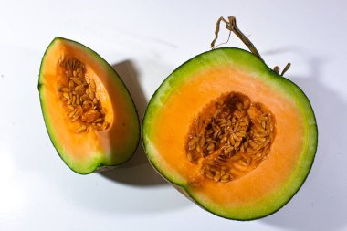 melon cut in half rounds and one quarter round, served on a plain white background