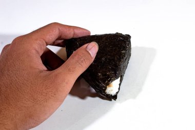 Geleneksel Japon yemekleri, pirinçle doldurulmuş, yosunlara sarılmış ve sol elde tutulan üçgen onigiri.