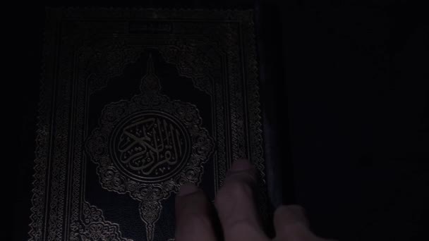 イスラム教の聖書を開く 金の文字で本のカバー 暗い背景にイスラム教の神聖な経典 4Kビデオ映像 南カリマンタン州 インドネシア 2023年4月17日 — ストック動画