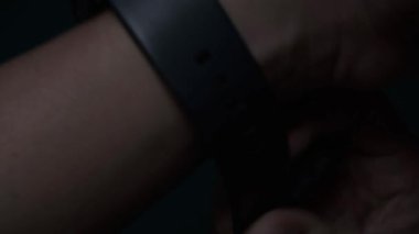 4K video görüntüleri. Başarılı bir adamın yakın çekimi bir saat takmaktır. Erkek eli ile. Siyah saati sol eline iki kez takmaya çalışan bir adam..