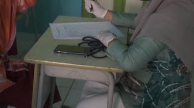 Başörtüsü, maskesi ve eldiveni olan Asyalı bir kadın doktor çocuğa sağlık danışmanlığı yapıyor..