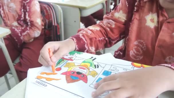 アジアの少年がクレヨンでキャラクターを着色し カラフルな創造性を示しています 上からの眺め 学校でのカラーリングレッスン — ストック動画