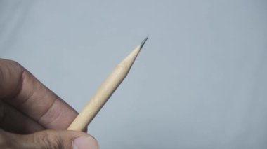 Bir adamın Asyalı eli ahşap bir kalemi sivriltip ucu izole edilmiş beyaz bir arka plana doğrultulana kadar çeviriyor. Kalem kurşununun keskinliğini gösteriyor, doğal ahşabı gösteriyor.. 