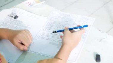 Bir öğrenci, bir okul sınavı sırasında cevapları bulmak için derin düşüncelere dalmış bir şekilde kalemini çeviriyor. Bu görüntü, odaklanmış projeler için ideal bir konsantrasyon ve düşünme anını yakalar. 4K