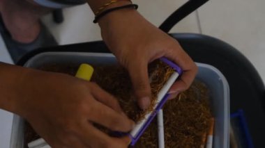 Yukarıdan aşağıya doğru tutulan el yapımı bir sigara sarma makinesi. Cihaz tütün ve kağıdı rulo için hazır tutuyor. Projeler için mükemmel. Güney Kalimantan, Endonezya. 25 Ocak 2025 
