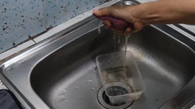 Mutfakta bulaşık yıkamak için sünger hazırlayan bir adam. Süngeri ıslatıyor ve mutfak aletlerini yıkamaya hazırlanıyor, pratik ve temiz bir mutfak sahnesi yaratıyor. Ev işleri ve temizlik projeleri için mükemmel.
