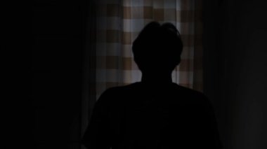 Gecenin karanlığında ellerini kaldırarak dua eden bir adamın silueti. Huzurlu bir ruhani an, sessiz ve duygusal bir atmosfer. Karanlık bir arka planda hafif bir ışık. Hayal kırıklığını ifade ediyor. 4K