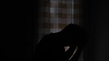 Hüsrana uğramış, karanlıkta duran bir adamın silueti. Duygusal bir an, umutsuzluk ve mücadele hislerini gölgelerde derin ve derin bir dalgın atmosferle yakalıyor. Duygusal bir an. 4K 