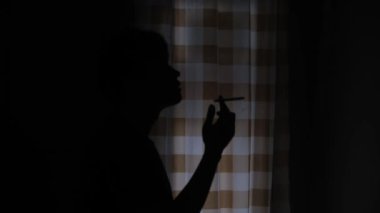 Tek başına sigara içen bir adamın silüeti, kendini hayatın sorunlarından arındırıyor. Karanlık ve kasvetli bir atmosferde sigara dumanının yükseldiği sessiz ve düşünceli bir an. Duygusal ve düşünceli bir sahne. 4k