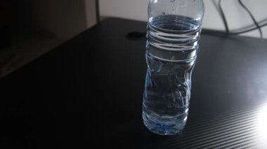 Masaya koyu siyah arka planlı tek bir şişe maden suyu konmuş. Minimalist ve temiz kompozisyon, hidrasyon, ürün gösterimi, sağlık veya reklamcılık konsepti projeleri için mükemmel