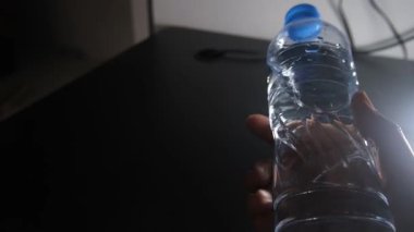 Bir şişe maden suyu kaldırıldı ve bir erkeğin eli tarafından döndürüldü. Şişe farklı açıları göstermek için döner, hidrasyon, ürün tanıtımı, sağlıklı yaşam tarzı ve günlük rutinler için idealdir.