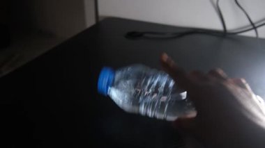 Siyah bir masanın üzerinde yan yatmış bir şişe içme suyu. Temiz şişe, karanlık yüzeyle çelişiyor. Ürün sergisi, su temaları ya da minimalist yaşam tarzı görselleri için mükemmel. görüntüler