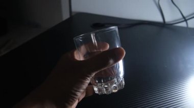 Siyah bir masadan kaldırılan şeffaf bir cam bardak. Güçlü karşıtlığa sahip temiz ve minimal hareket, içecek içeriği, ürün sunumu ve modern yaşam tarzı görselleri için ideal