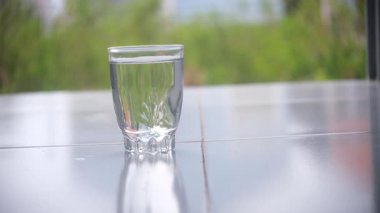 Masadaki birbirinin aynısı bir bardağın yanına maden suyu dolu temiz bir bardak koymak. Doğal ışıklandırma ile temiz, basit bir düzen, hidrasyon teması, sağlıklı yaşam tarzı ve içecek için ideal..