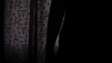 Sabah yatak odasının perdelerini açan bir adamın silüeti. Yumuşak ışığın odaya girdiği huzurlu bir an. Sabah rutini, sakin atmosfer, günün yeni başlangıcı.