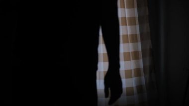 Bir adamın silueti ön kapının perdesini açıyor ve uzaklaşıyor. Huzurlu bir sabah ışığı, sakin bir an, ev atmosferi, iç gözlem ve sinema sahnesi. 4K görüntüler. video.