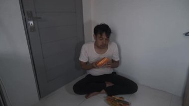 Yıpranmış gömlekli fakir bir adam iki eliyle açgözlülükle olgun papaya yiyor. Meyveyi yerken yüzü aciliyeti ve ihtiyacı yansıtıyor. Sahne, güçlü, gerçek bir anı temsil ediyor.