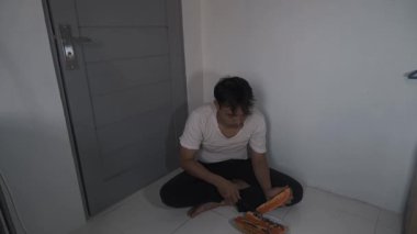 Soluk beyaz gömlekli bir adamın olgun bir papayadan tohumları ayırdığı görülüyor. Elleri, basit ve doğal bir gıda hazırlama sürecine odaklanarak siyah tohumları dikkatlice çıkarıyor. Yakın çekim yüksekliği.