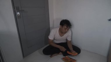 Giyinik beyaz gömlek giyen bir adam papaya tohumlarını elle ayırıyor. Yakın plan, doğal besin hazırlama sürecini yakalar, dikkatini ve meyvenin dokusunu gösterir. Sahne vurgulanıyor.