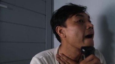 Bir adam sakalını elektrikli traş makinesiyle dikkatlice tıraş eder, pürüzsüz ve pürüzsüz olduğundan emin olmak için yavaşça hareket eder. Onun odaklanmış ifadesi rutin kişisel bakım ve kişisel bakımı yansıtıyor..