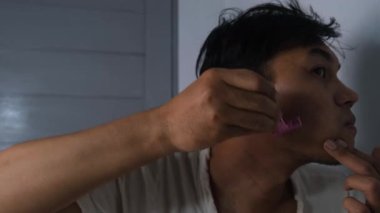 Zavallı bir adam pembe bir elle tıraş oluyor. Giysilerine ve mütevazı görünüşüne rağmen dikkatle odaklanarak kendini tımar ediyor. Sahne gerçek bir kişisel hijyen anını yakalıyor. 4K