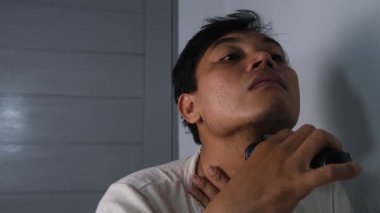 Bir adam sakalının sağ ve sol taraflarını odaklanma ve özenle tıraş eder, dengeli ve temiz bir görünüm hedefler. Bakım rutini kişisel hijyen, günlük bakım ve kendine bakımı vurguluyor..