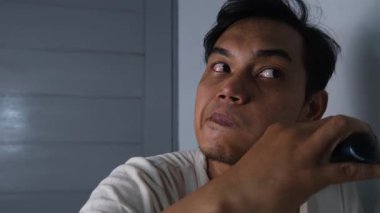 Bir adam sakalını tıraş makinesi kullanarak yavaşça tıraş eder, temiz ve eşit bir sonuç için dikkatlice hareket eder. Odaklanmış ifadesi, kişisel bakım ve detaylara dikkat çekiyor. Sahne, her gün sakin bir kişisel bakım ve hijyen anı yakalıyor..