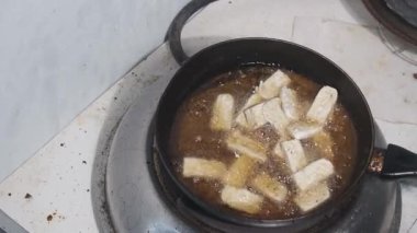 Çiğ tempeh parçaları tavada kızartılmak üzere kızgın yağın içine yerleştiriliyor. Süreç, kızgın yağ ve taze malzemeler gösterilerek geleneksel Endonezya tempehinin pişirilmesinin başlangıcını yakalıyor. Sahne yüksek