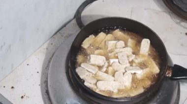 Sıcak yağda kızartılan Tempeh dilimleri, altın kahverengiye dönüşürken tavada fokurdarlar. Geleneksel Endonezya soya bazlı gıda pişirme işlemi sırasında yağ sıçramaları ve artmasıyla cızırdıyor. 4K