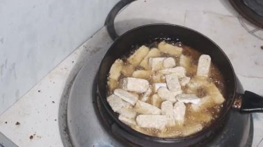 Siyah bir tavada yemek pişirirken hafif bir tempeh karışımı. Geleneksel Endonezya soya bazlı gıda tavada yavaşça hareket ederken cızırdıyor. Sahne, yemek pişirme sürecinin yakın çekim anını yakalar.