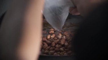 Çiğ fıstık kaynayan sıcak yağda kızartılıyor ve yavaşça kahverengiye dönüşürken cızırdıyor. Yağ yer fıstıklarının etrafında dolaşarak zengin bir doku ve renk yaratıyor. Bu yemek sahnesi yakalıyor. 4K