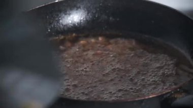 Geleneksel el yapımı yağ süzgeci kullanarak fıstık kızartma işlemi. Görüntüler yerel yemek pişirme tekniğini fındıkların etrafında kaynar yağ fokurdarken yakalıyor. Stok görüntüleri için uygun. 4K