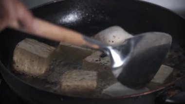Ofu parçaları tavanın içinde kızgın yağda kızartılıyor. Altın kahverengiye pişirilirken cızırdıyor. Hareket, kaynayan yağda dalgalanmalar yaratarak kızartma sürecini vurguluyor. Bu sahne kaydediyor. 4K